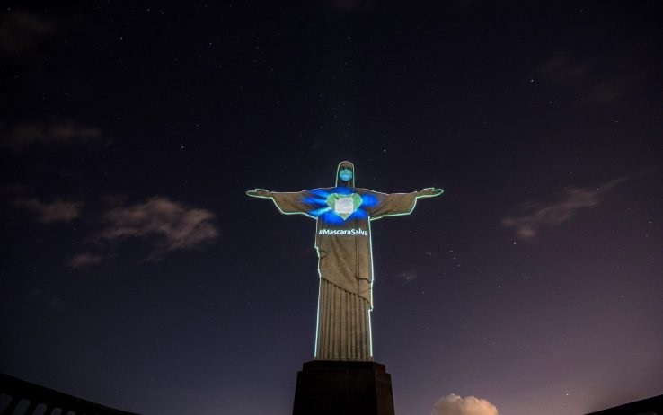 CORONAVIRUS. LA STATUA DEL CRISTO DI RIO INDOSSA LA MASCHERINA