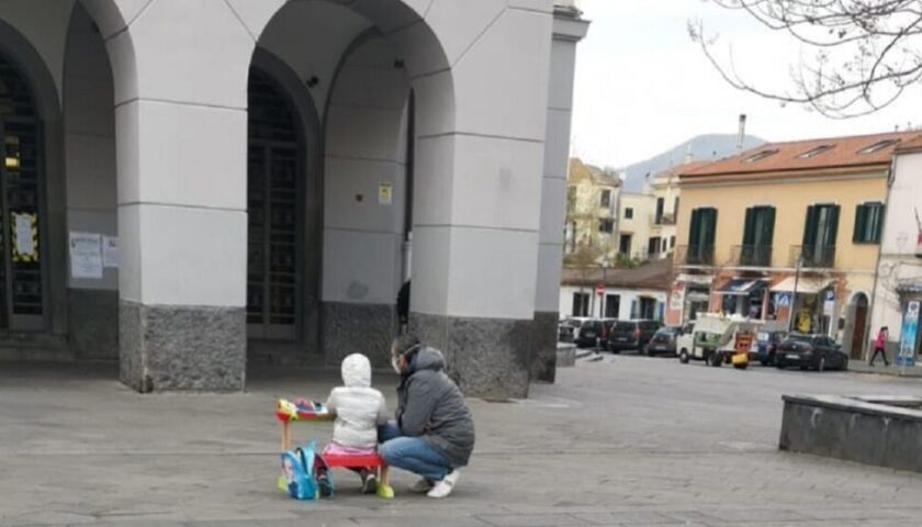 Scuole chiuse a Cava de’ Tirreni, bambina con un banco davanti al Comune